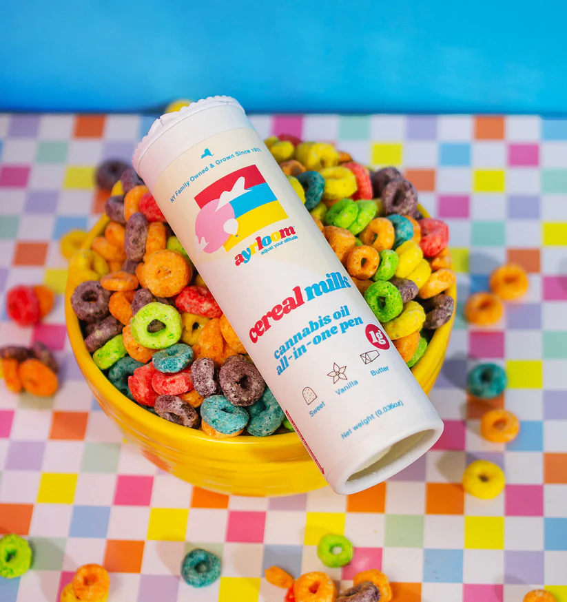 Product display of the Ayrloom Cereal Milk 1g cannabis oil all-in-one vape pen next to its white cylindrical packaging tube, featured against a clean white background with a teal circular graphic.