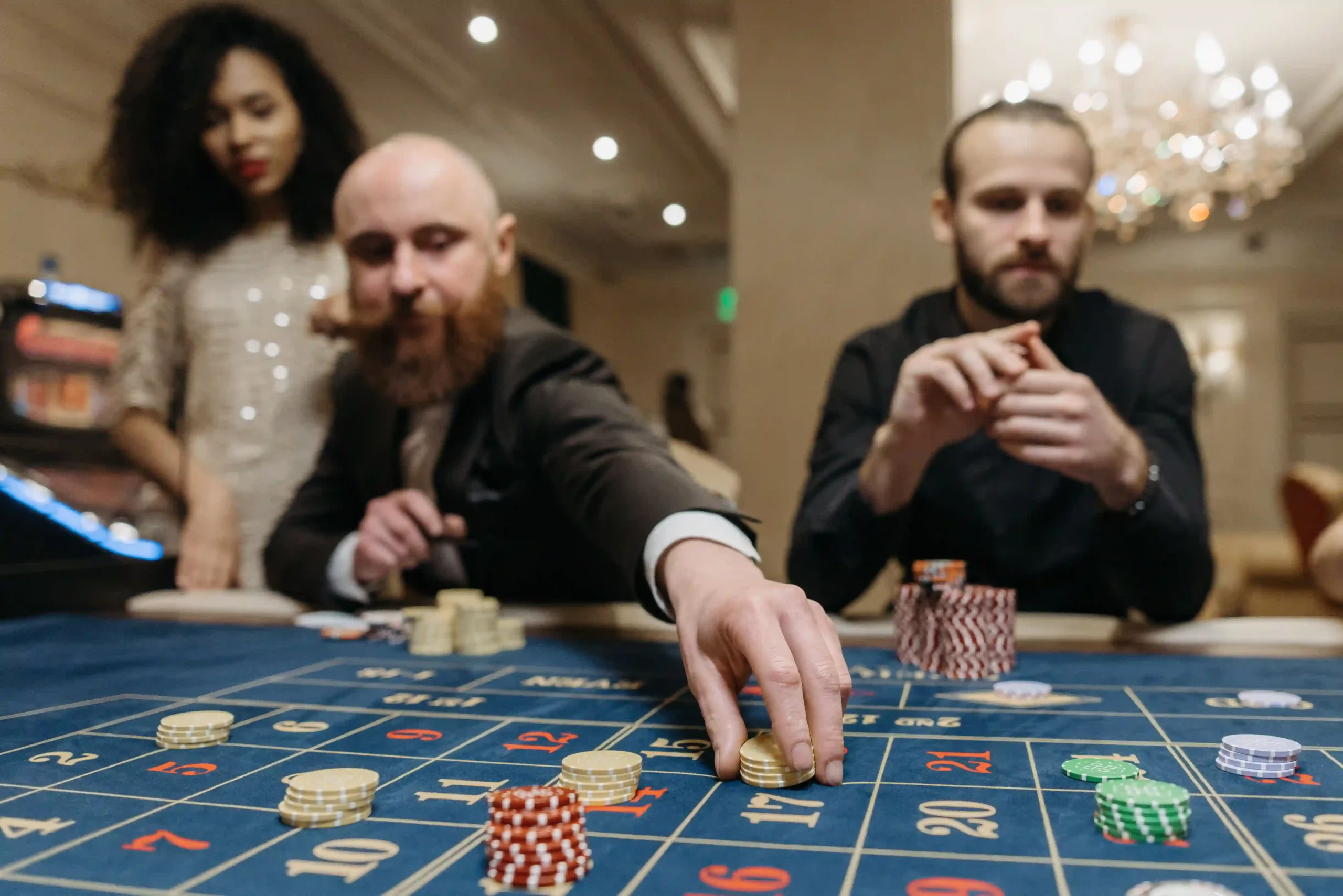 Guests placing bets with chips on a casino floor table game, highlighting compliance with property rules and casino regulations.